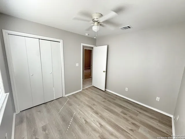 wooden floor in an empty room with a ceiling fan