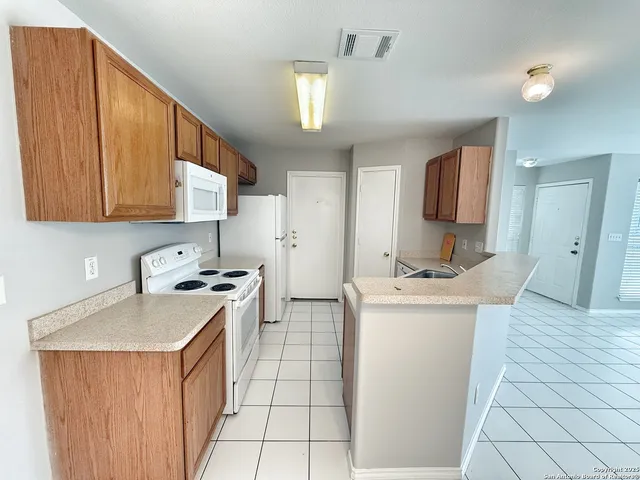 a kitchen with a sink a stove cabinets and a living room