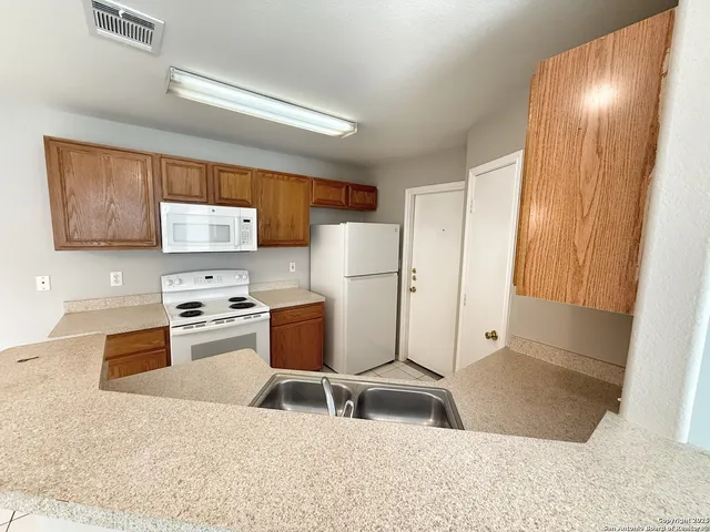a kitchen with stainless steel appliances kitchen island granite countertop a refrigerator a stove top oven a sink and dishwasher