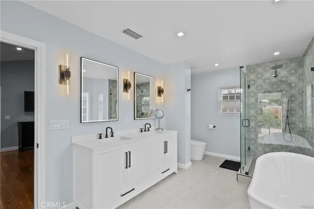 a spacious bathroom with a double vanity sink a large mirror and a bathtub
