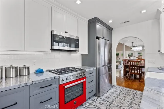 a kitchen with granite countertop a refrigerator stove and wooden floor