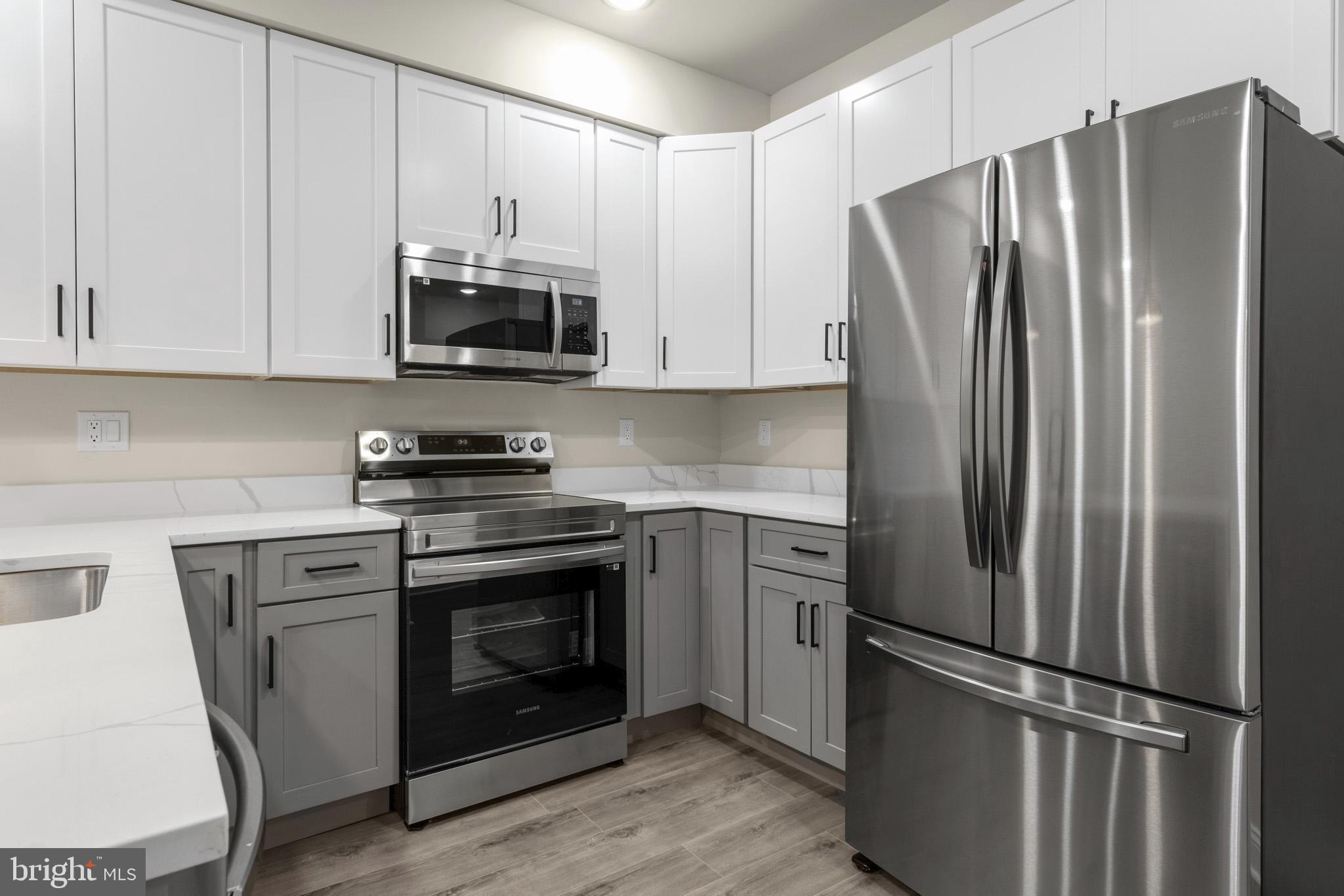 a kitchen with stainless steel appliances white cabinets white stove a refrigerator and a microwave