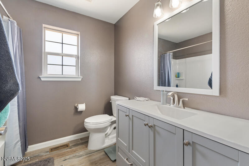 4609 Rancheria Road Fallon, NV 89406 - Photo 19 of 25 a bathroom with a toilet a sink a mirror and a window