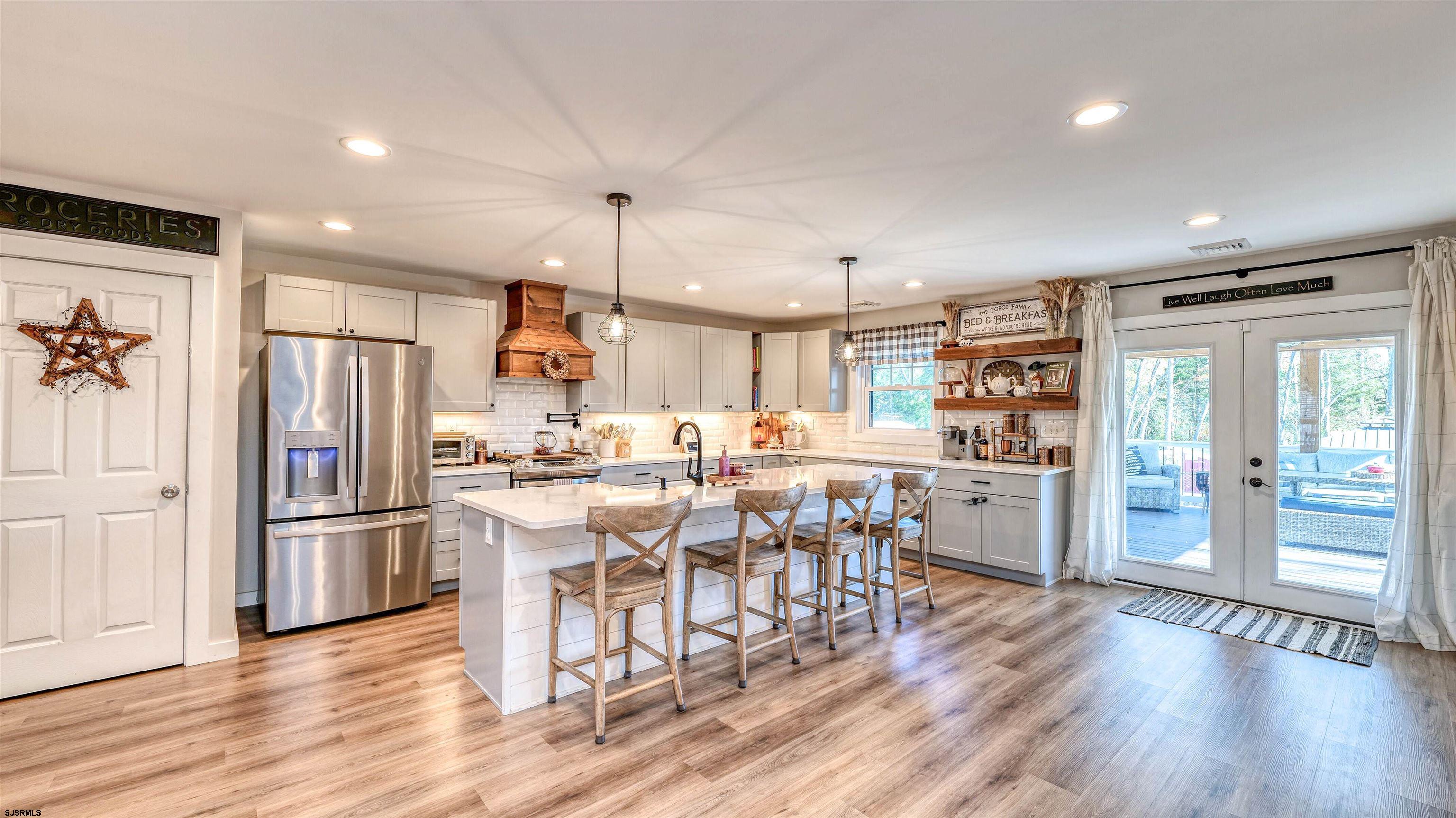 130 Stage Road Little Egg Harbor, NJ 08087 - Photo 15 of 50 a kitchen with stainless steel appliances kitchen island granite countertop a refrigerator a stove a sink a dining table and chairs with wooden floor