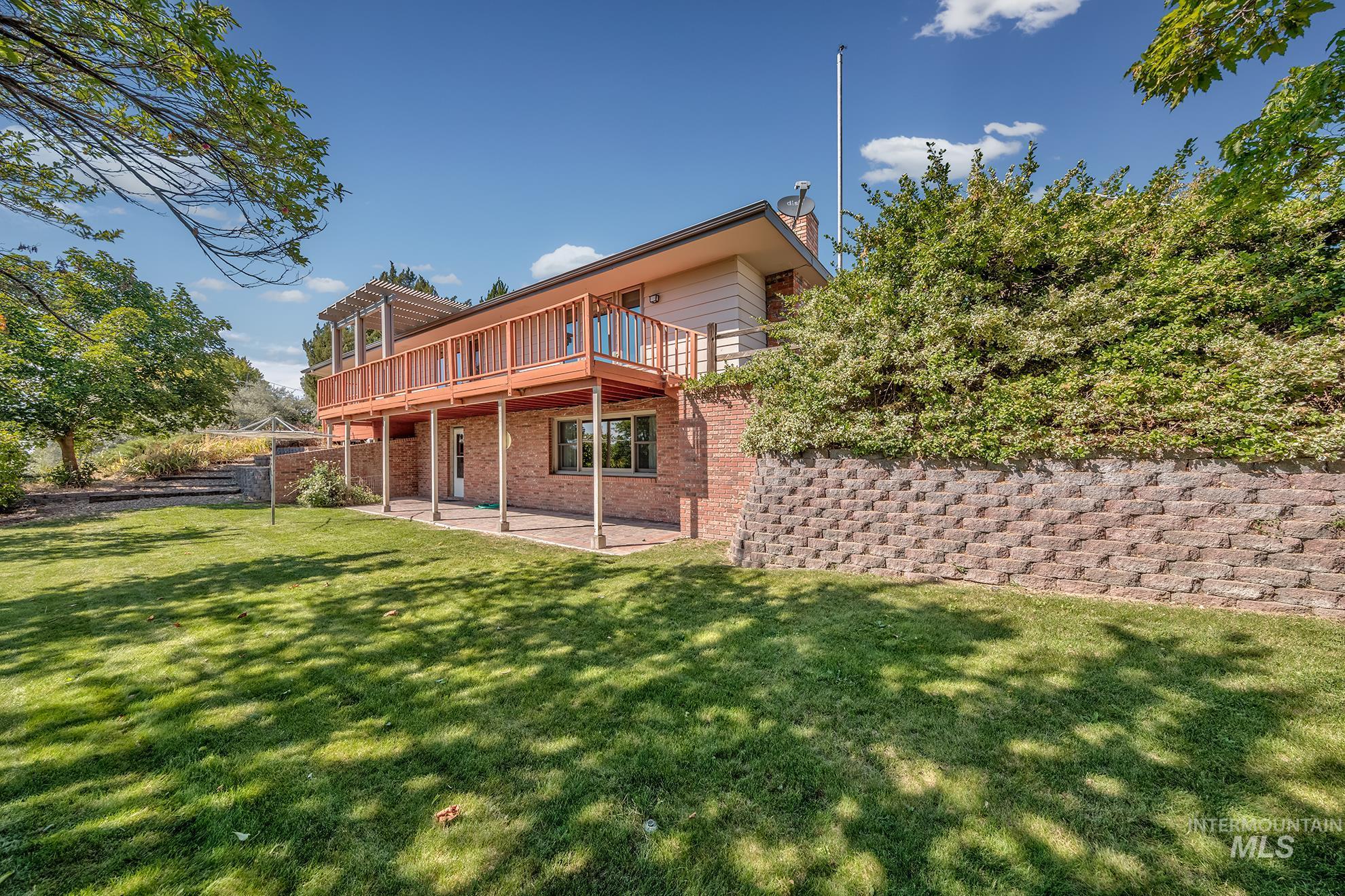 1493 Cove Road Weiser, ID 83672 - Photo 38 of 50 Expansive terraced backyard featuring a large green lawn, mature trees, and a retaining wall