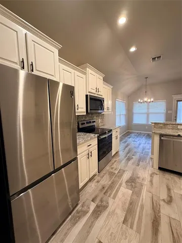 a kitchen with granite countertop a refrigerator stove and microwave
