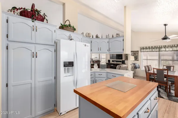 a kitchen with stainless steel appliances kitchen island granite countertop a refrigerator a stove and white cabinets with wooden floor