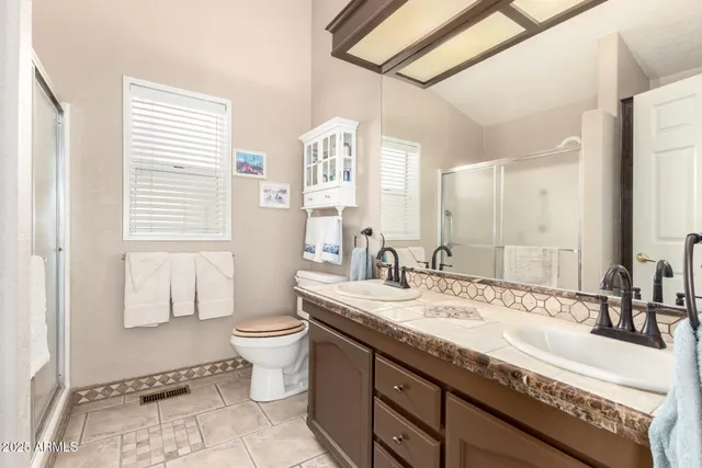 a bathroom with a granite countertop sink a toilet a mirror and shower