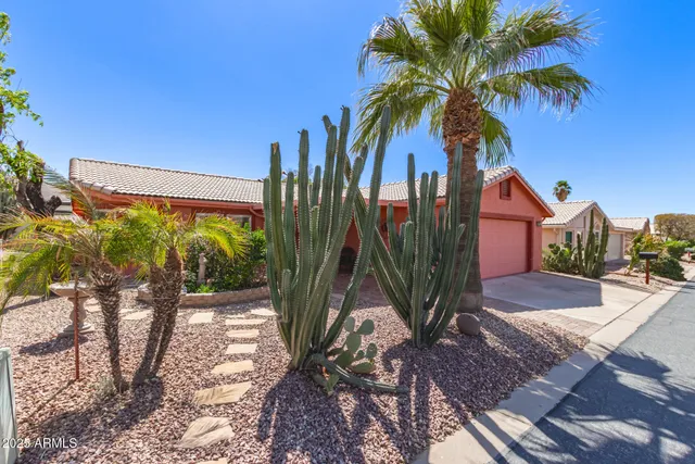 a view of a palm trees front of house with wooden fence
