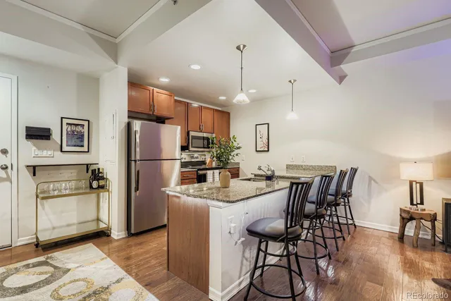 a kitchen with stainless steel appliances kitchen island granite countertop a refrigerator a stove a kitchen island with a dining table and chairs