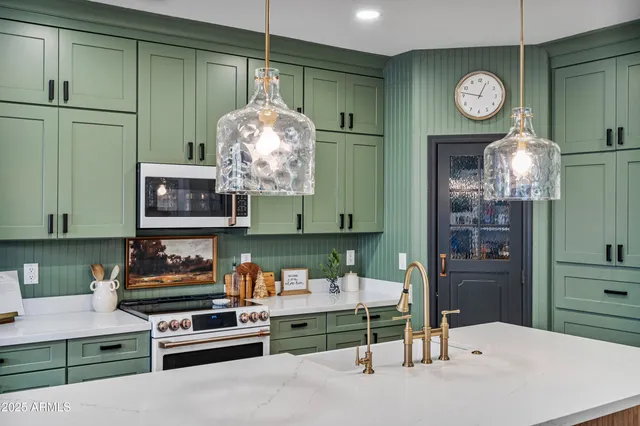 a large kitchen with kitchen island a stove a sink a refrigerator and a fireplace