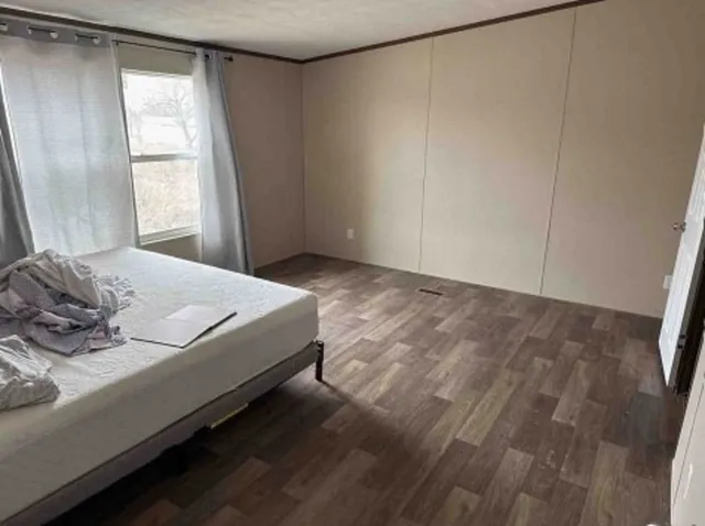 a bedroom with a bed and a window with wooden floor