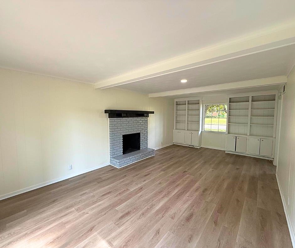 3969 Millbranch Road Memphis, TN 38116 - Photo 15 of 33 Unfurnished living room with wood finished floors, a fireplace, and beamed ceiling