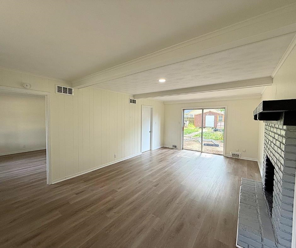 3969 Millbranch Road Memphis, TN 38116 - Photo 17 of 33 Unfurnished living room featuring wood finished floors, beamed ceiling, and a brick fireplace