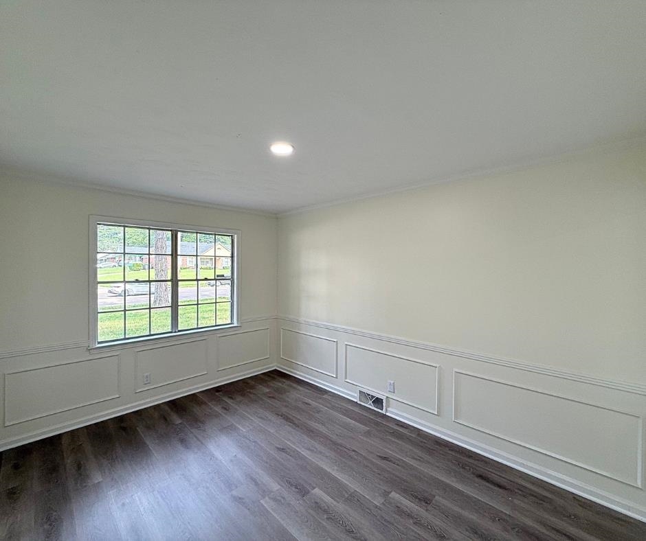 3969 Millbranch Road Memphis, TN 38116 - Photo 6 of 33 Unfurnished room with crown molding, recessed lighting, dark wood-style floors, wainscoting, and a decorative wall