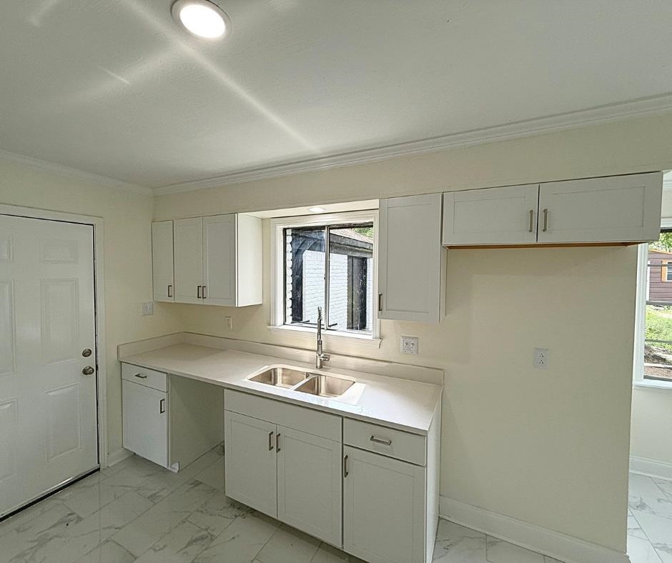 3969 Millbranch Road Memphis, TN 38116 - Photo 8 of 33 Kitchen featuring light marble finish floors, ornamental molding, white cabinetry, and light countertops