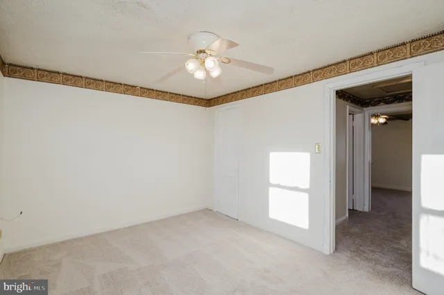 a view of an empty room with chandelier fan