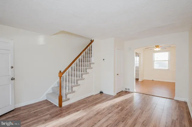 a view of an empty room with wooden floor and stairs
