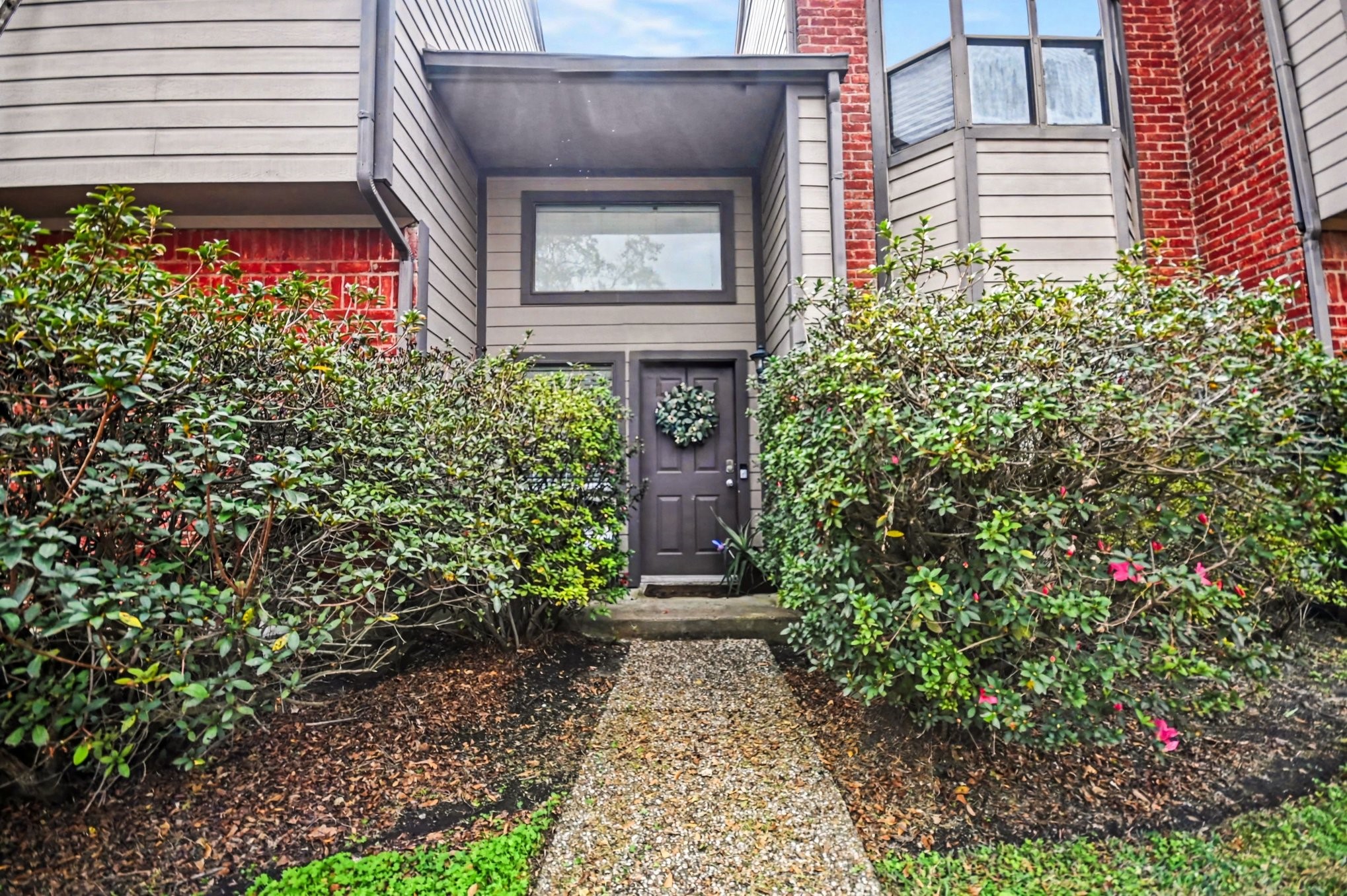7447 Cambridge Street, Unit 73 Houston, TX 77054 - Photo 1 of 27 a front view of a house with lots of flowers