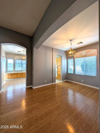 a view of an empty room with window and wooden floor