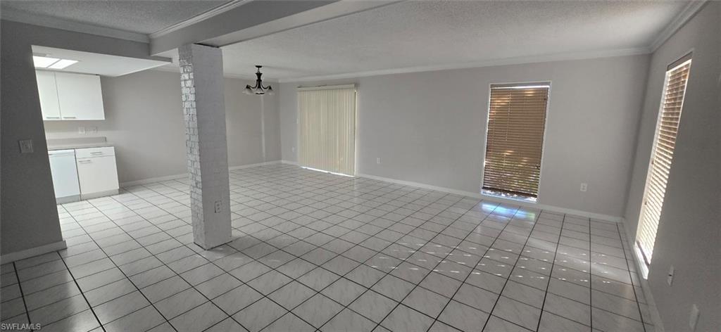 925 Palm View Drive, Unit 121 Naples, FL 34110 - Photo 2 of 13 Unfurnished living room featuring a textured ceiling, crown molding, and light tile patterned flooring
