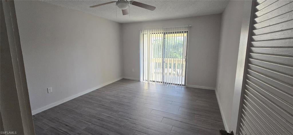 925 Palm View Drive, Unit 121 Naples, FL 34110 - Photo 3 of 13 Unfurnished room with a textured ceiling, dark wood-type flooring, and a ceiling fan
