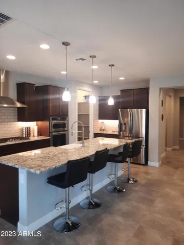 a kitchen with stainless steel appliances kitchen island granite countertop a table chairs sink and cabinets
