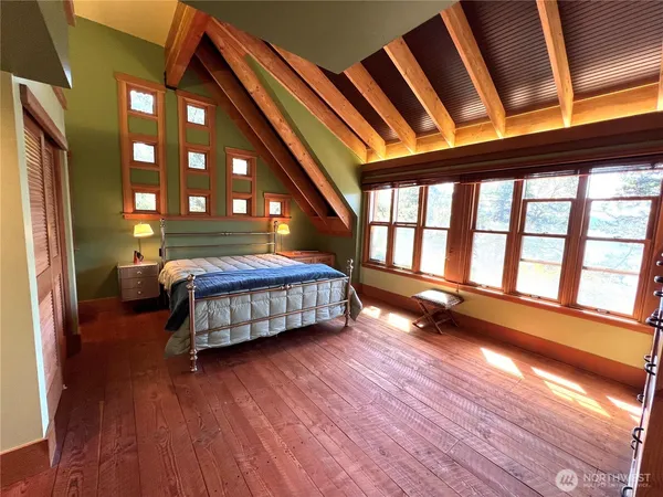 a bedroom with a bed and a large window with wooden floor