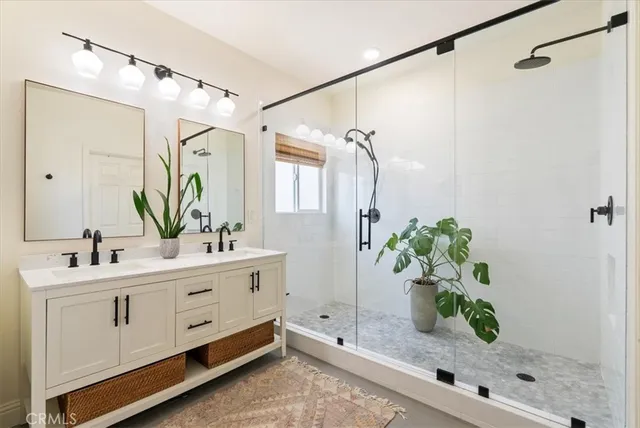 a bathroom with a sink a mirror a potted plant and a shower