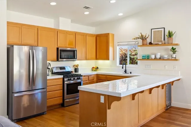 a kitchen with stainless steel appliances granite countertop a refrigerator a stove top oven a sink and dishwasher with wooden floor