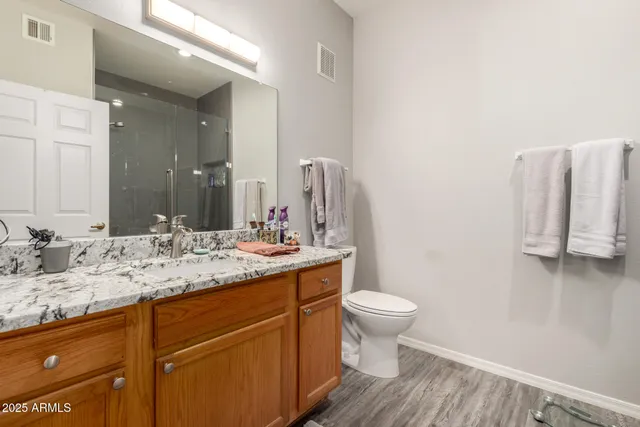 a bathroom with a granite countertop sink toilet and mirror