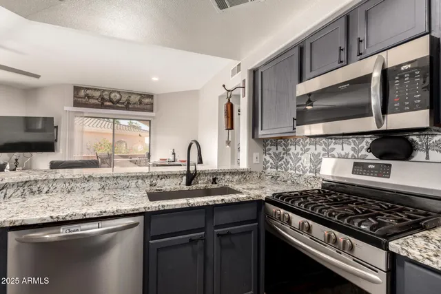 a kitchen with granite countertop a sink stove top oven and cabinets