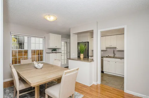 a kitchen with granite countertop a dining table chairs and refrigerator