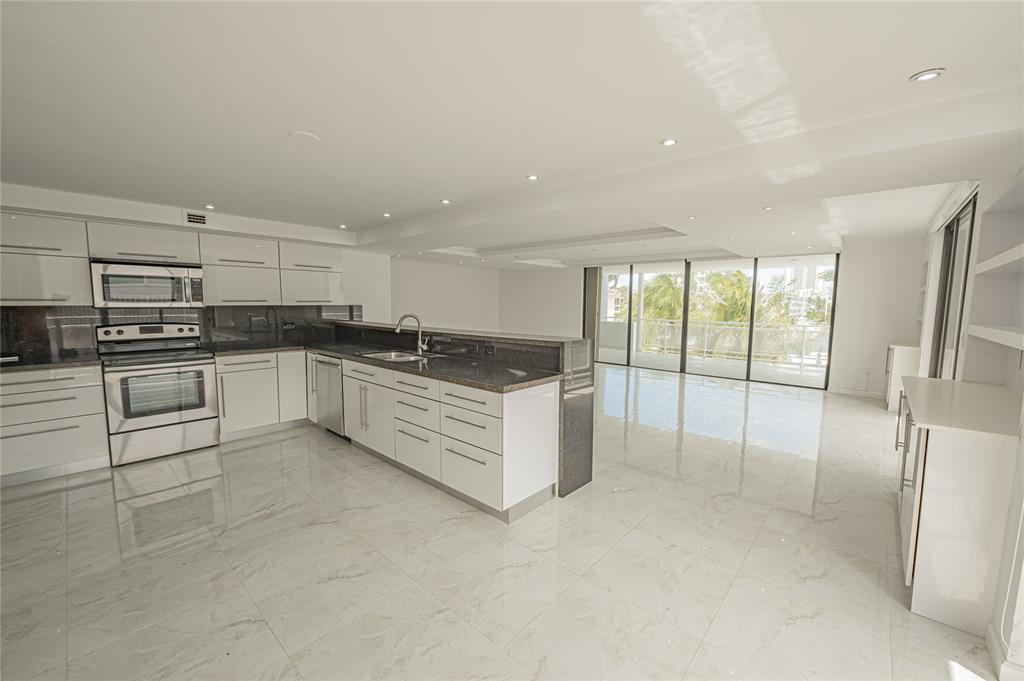 468 Golden Isles Drive, Unit 402 Hallandale Beach, FL 33009 - Photo 21 of 53 a large white kitchen with stainless steel appliances granite countertop a stove and a refrigerator