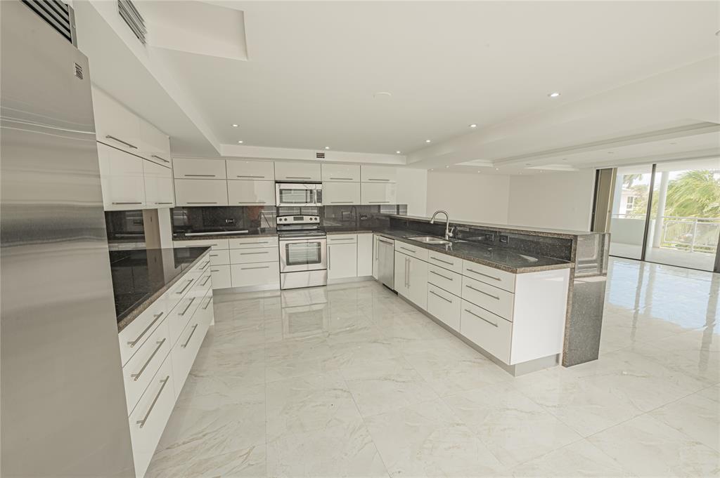468 Golden Isles Drive, Unit 402 Hallandale Beach, FL 33009 - Photo 22 of 53 a large white kitchen with stainless steel appliances granite countertop a stove and a sink
