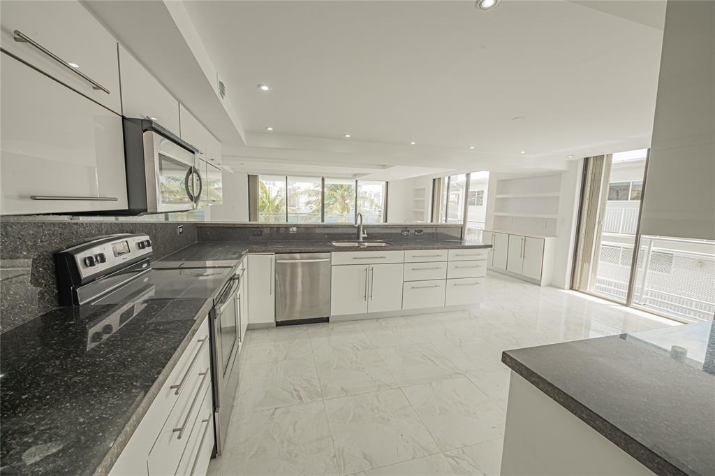 468 Golden Isles Drive, Unit 402 Hallandale Beach, FL 33009 - Photo 23 of 53 a kitchen with stainless steel appliances granite countertop a sink stove and refrigerator