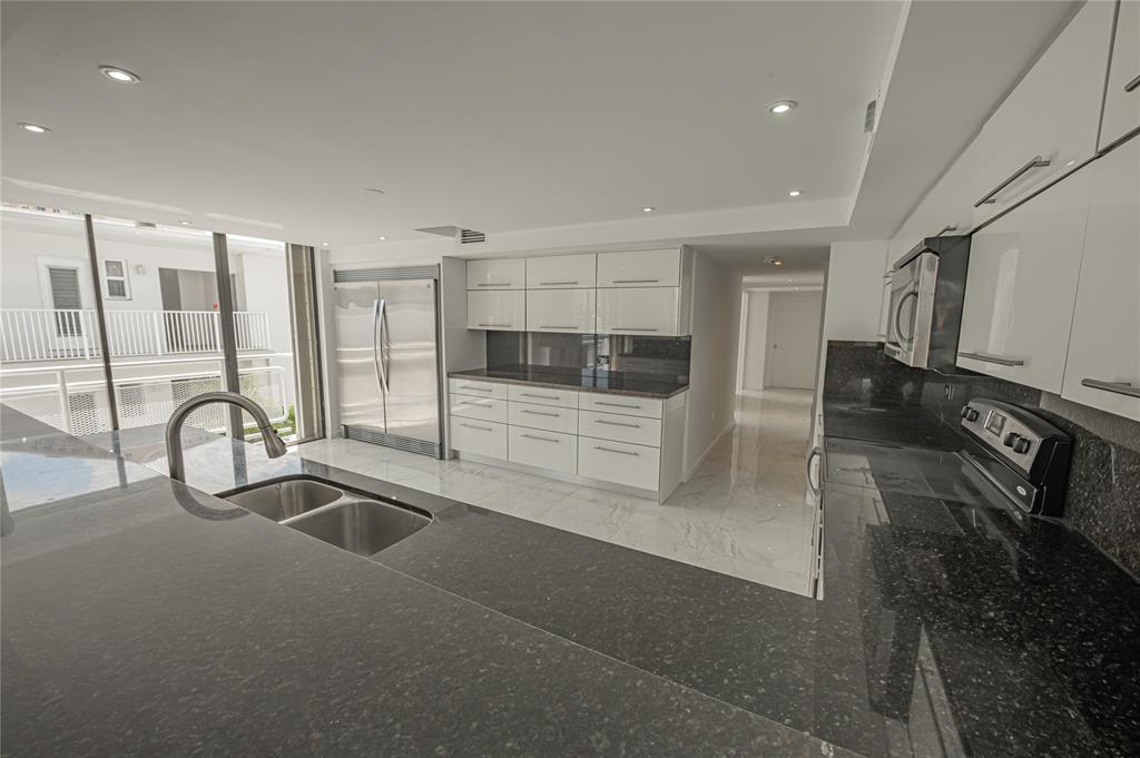 468 Golden Isles Drive, Unit 402 Hallandale Beach, FL 33009 - Photo 26 of 53 a kitchen with stainless steel appliances kitchen island granite countertop a sink and cabinets