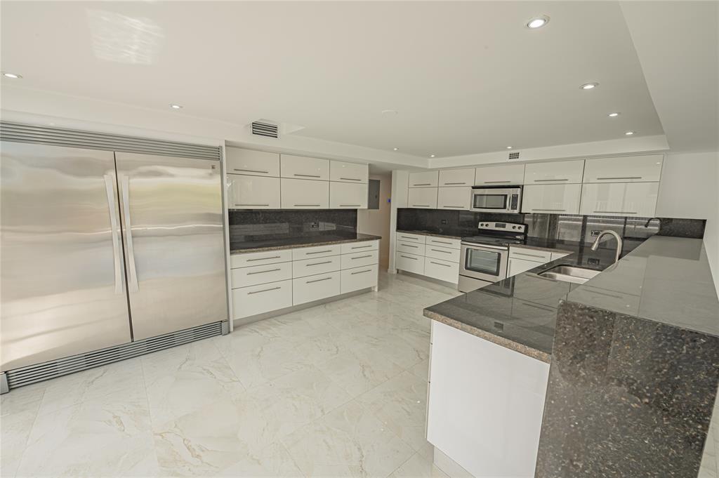 468 Golden Isles Drive, Unit 402 Hallandale Beach, FL 33009 - Photo 27 of 53 a kitchen with stainless steel appliances granite countertop a refrigerator a stove and a sink with wooden floors