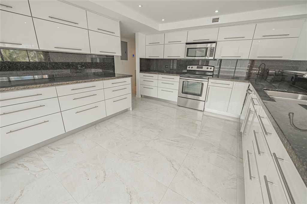 468 Golden Isles Drive, Unit 402 Hallandale Beach, FL 33009 - Photo 28 of 53 a kitchen with stainless steel appliances granite countertop a sink and a stove