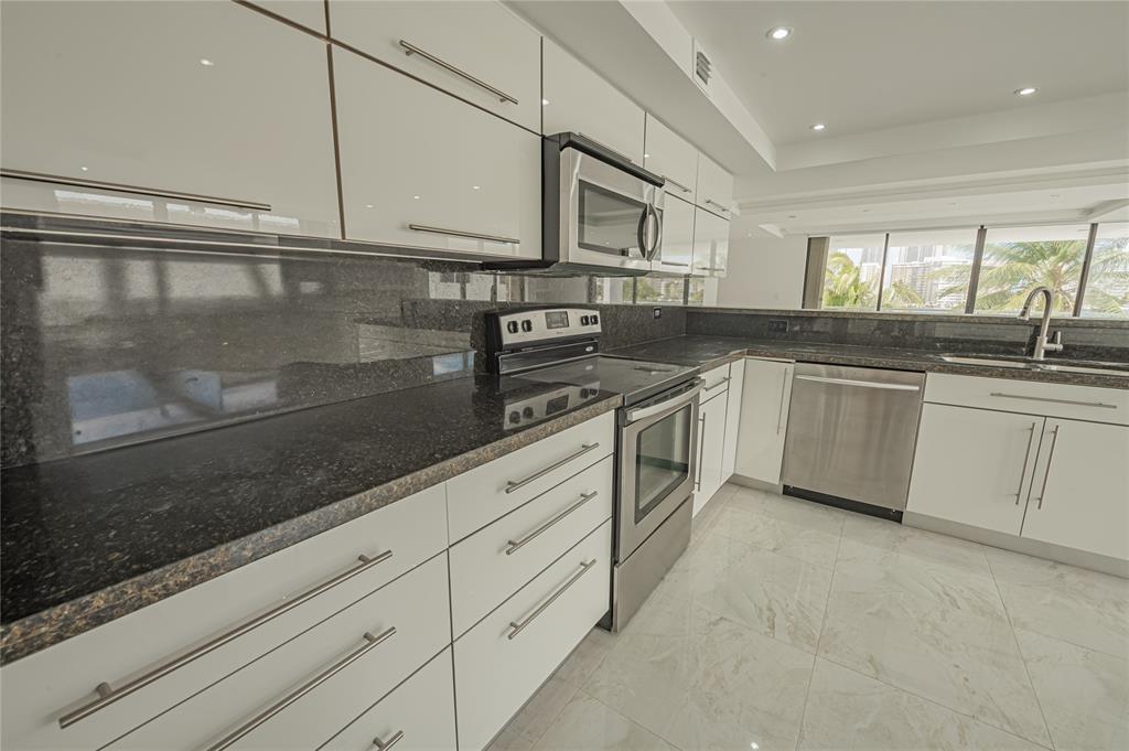 468 Golden Isles Drive, Unit 402 Hallandale Beach, FL 33009 - Photo 29 of 53 a kitchen with stainless steel appliances granite countertop a sink and cabinets