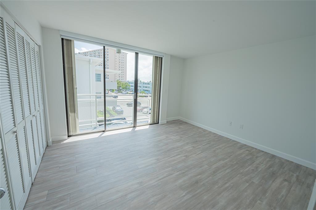 468 Golden Isles Drive, Unit 402 Hallandale Beach, FL 33009 - Photo 36 of 53 a view of an empty room with wooden floor and a window