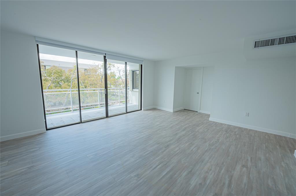 468 Golden Isles Drive, Unit 402 Hallandale Beach, FL 33009 - Photo 39 of 53 an empty room with wooden floor and balcony