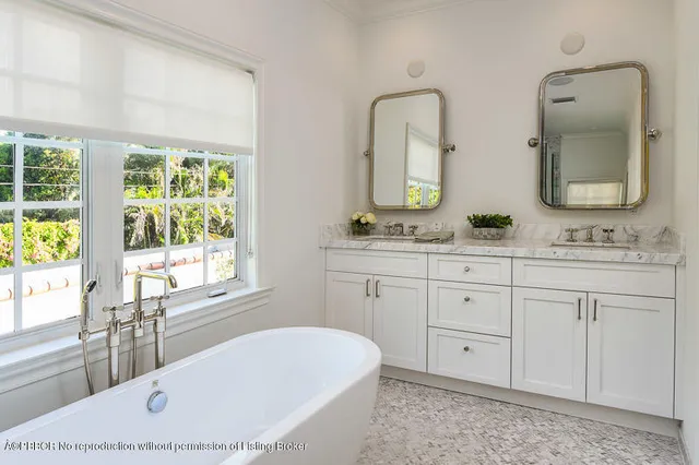 a bathroom with a double vanity sink bathtub large mirror and window