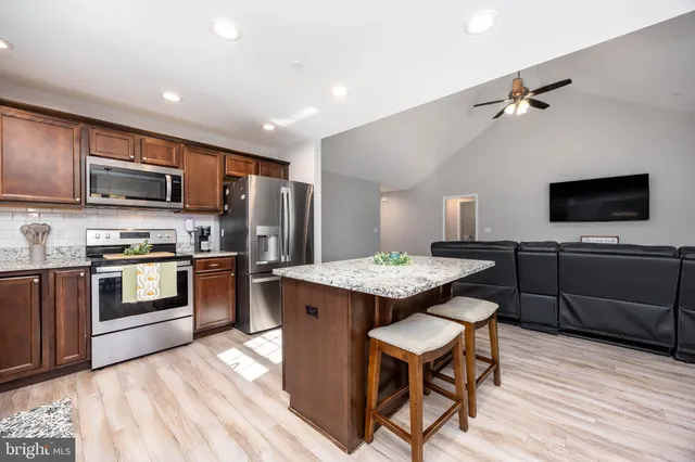 a kitchen with granite countertop stainless steel appliances a sink window and cabinets