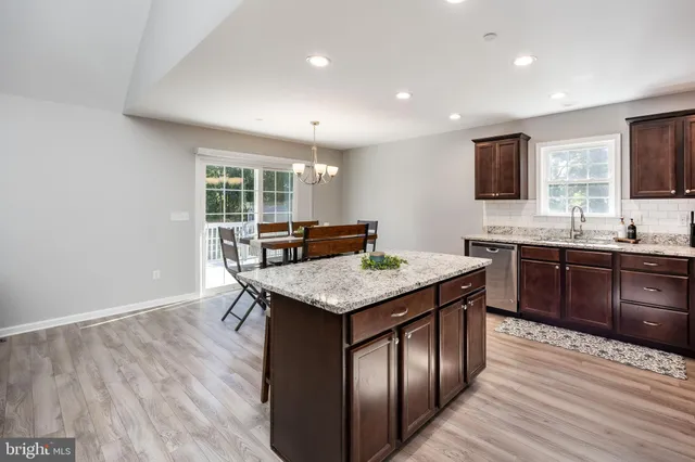 a kitchen with a stove a sink a dining table and chairs with wooden floor