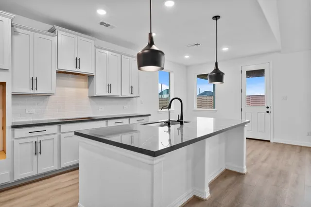 a kitchen with granite countertop a sink a counter space appliances and cabinets