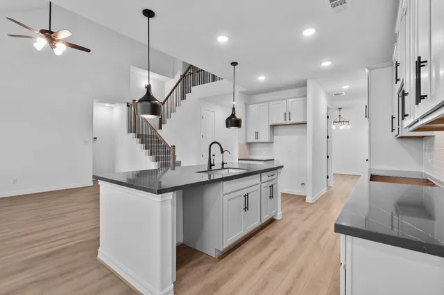 a kitchen with granite countertop a sink a counter space appliances and cabinets