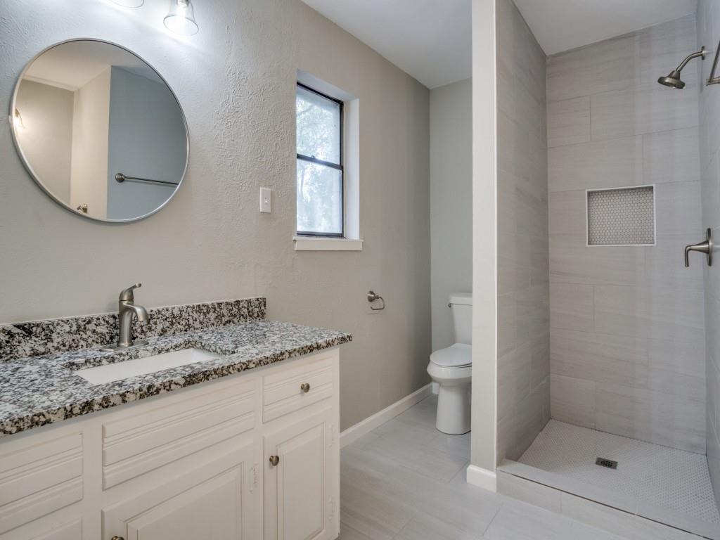 9523 Bellechase Road Granbury, TX 76049 - Photo 21 of 25 a bathroom with a granite countertop toilet a sink and mirror