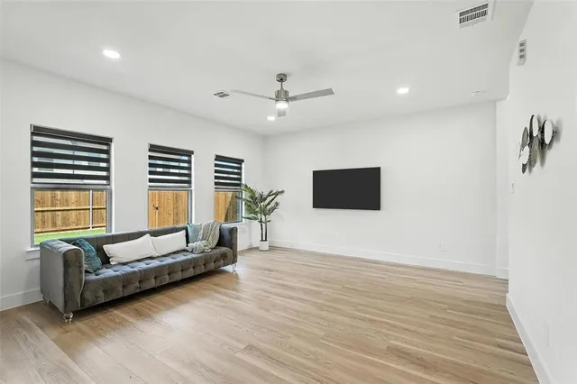 a living room with furniture a flat screen tv and a wooden floor