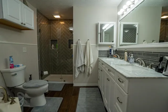 a bathroom with a granite countertop sink toilet and shower